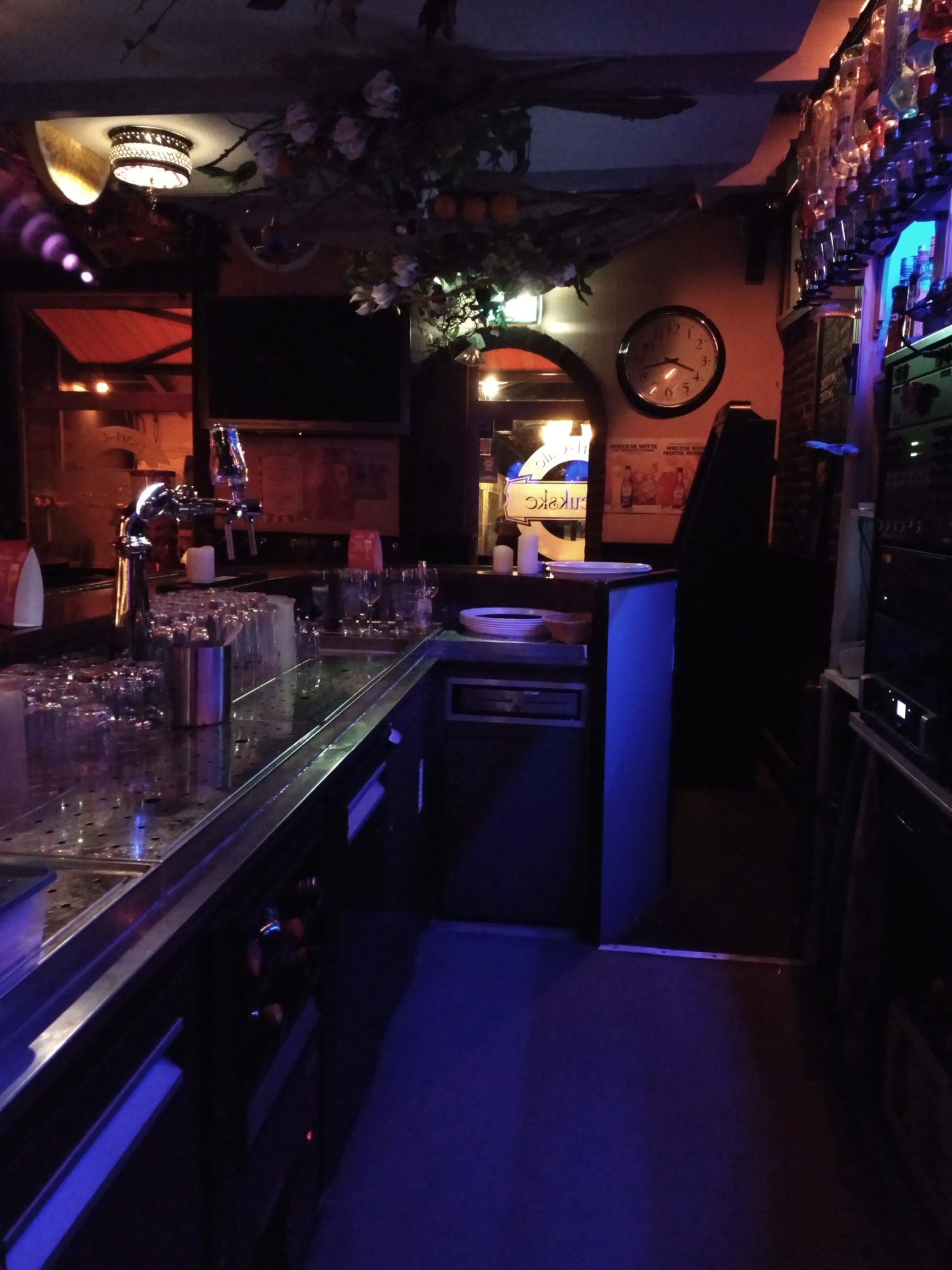 De bar van ’t Heukske in de avond, met blauw licht, de tap en glazen