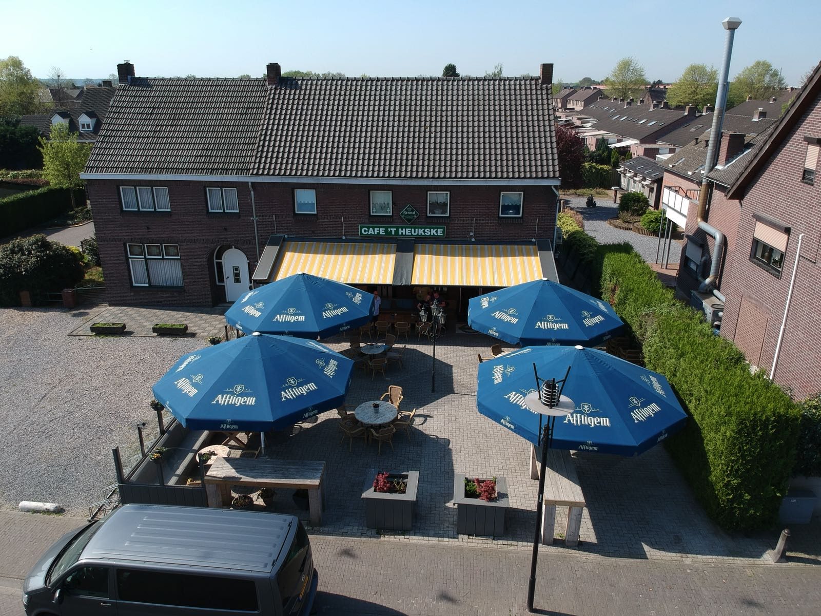 Het pand en het hele terras van bovenaf, met zes parasols