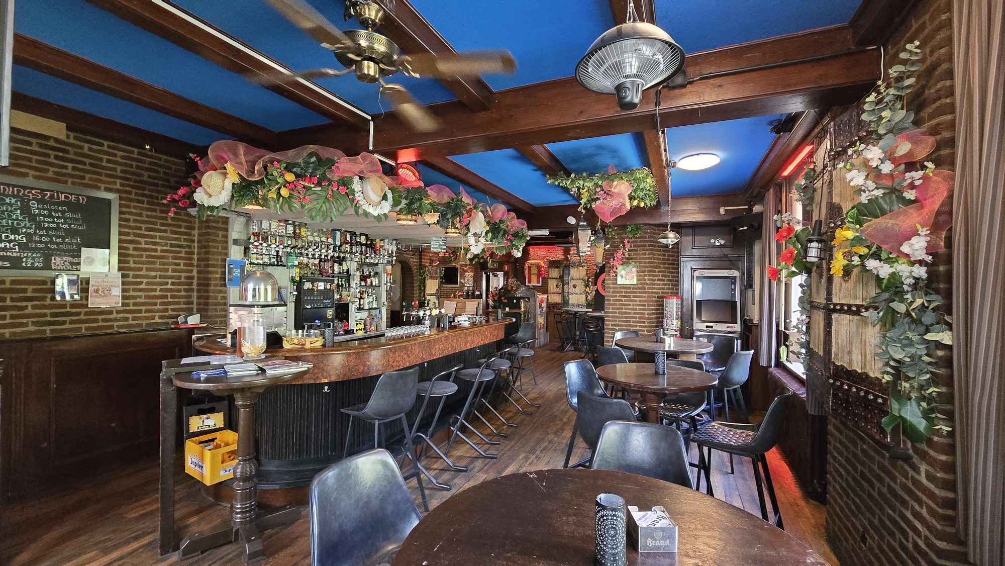 De houten bar met barkrukken en bloemen onder het blauwe plafond